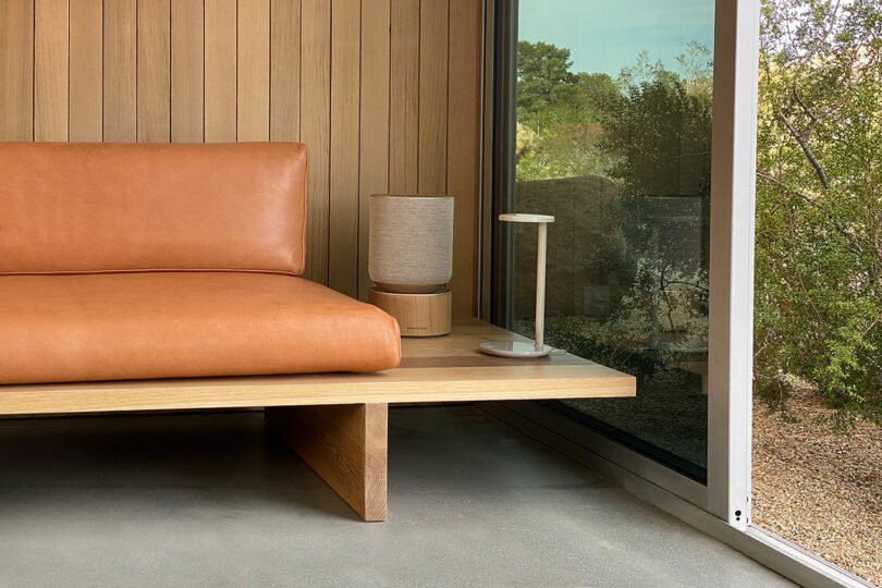 partial view of modern platform wood sofa with orange leather cushions