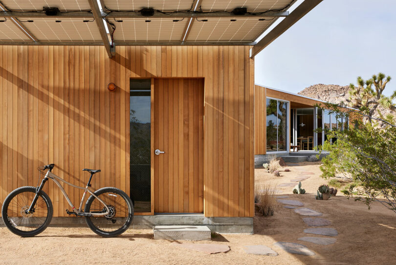exterior shot of end of modern wood house in desert with bicycle propped against house