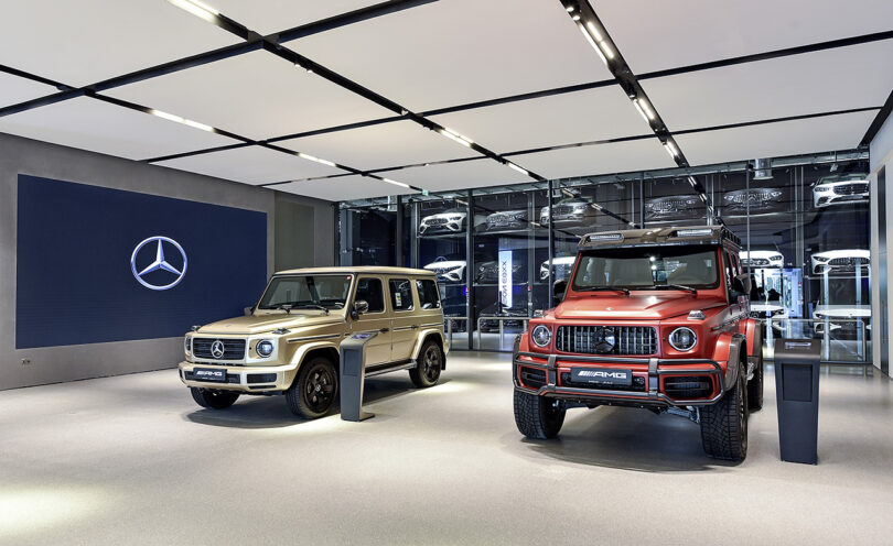 Mercedes-Benz Brand Center in Dubai interior showroom with two AMG SUVs parked in front of large screen.