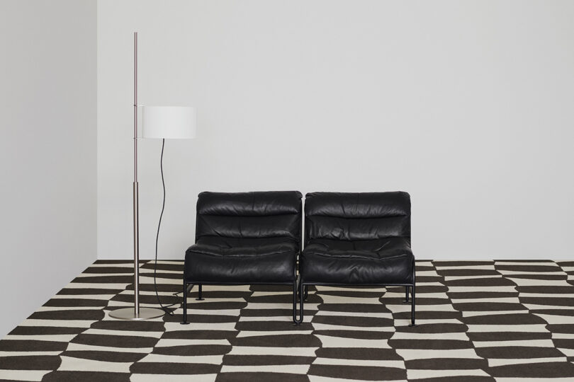 black and white patterned rug with two black chairs and a floor lamp