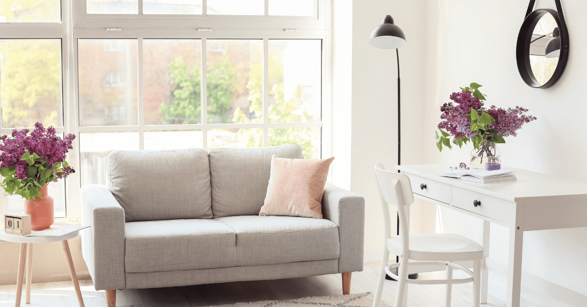 A chic room with grey couch and flowers used as decor.