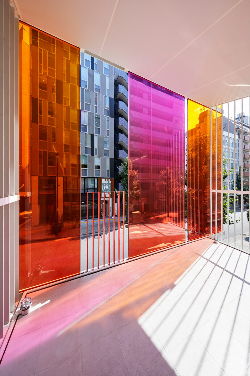 angled interior view of modern office space looking out to balcony with orange, pink and yellow exterior glass