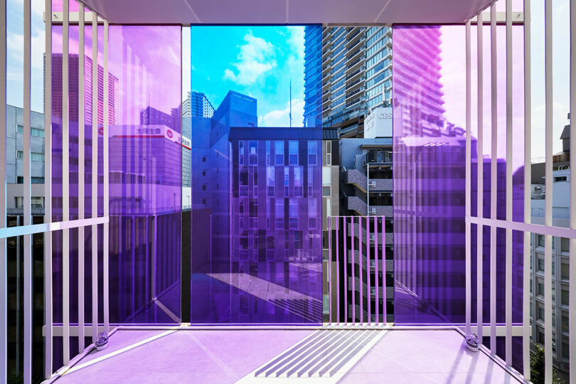 angled interior view of modern office space looking out to balcony with blue and purple exterior glass