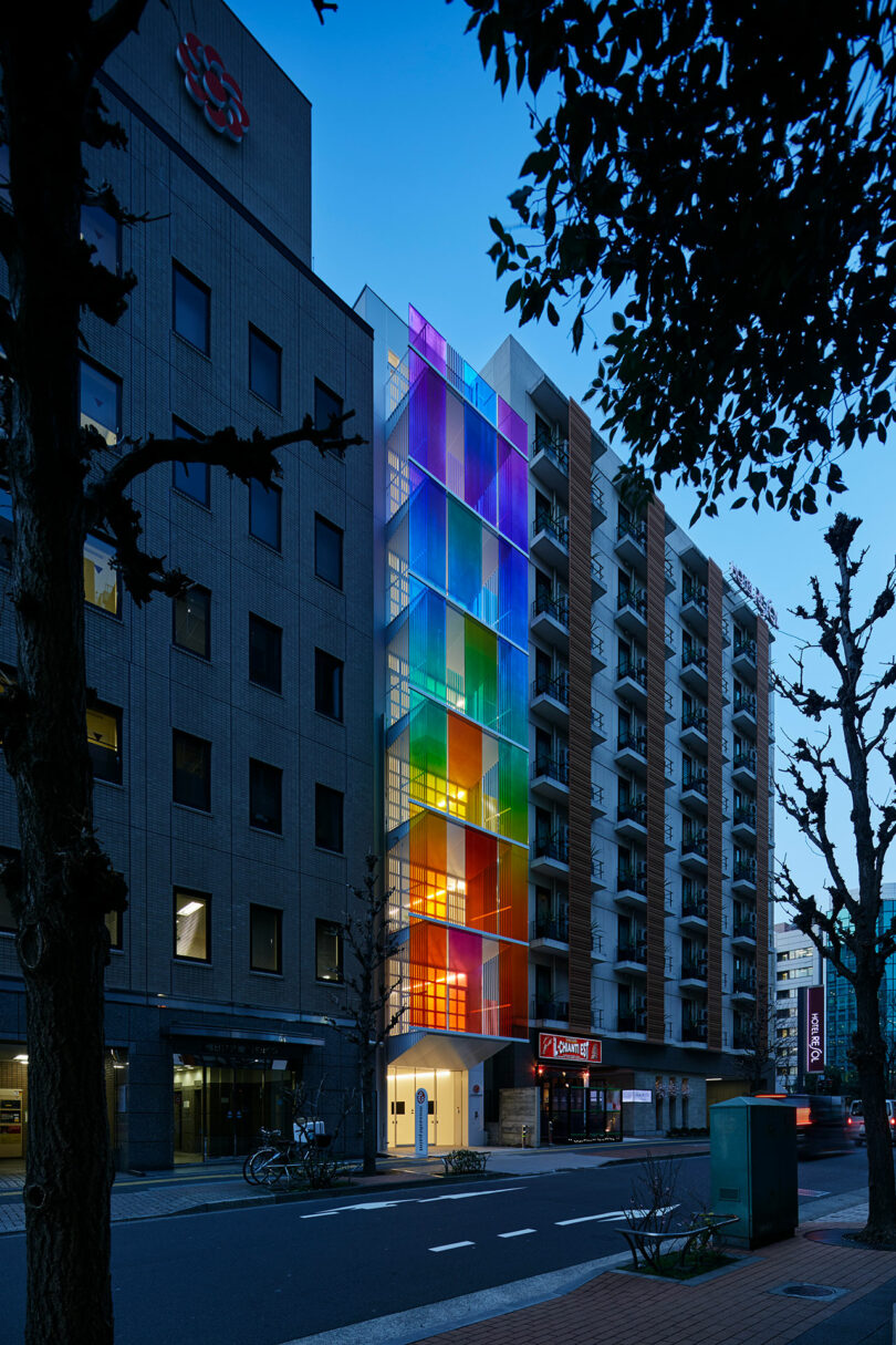 angled evening exterior view of modern building with rainbow fronted facade