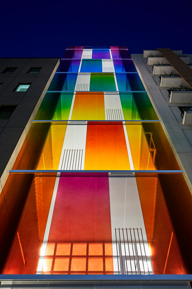 upward evening exterior view of modern building with rainbow fronted facade