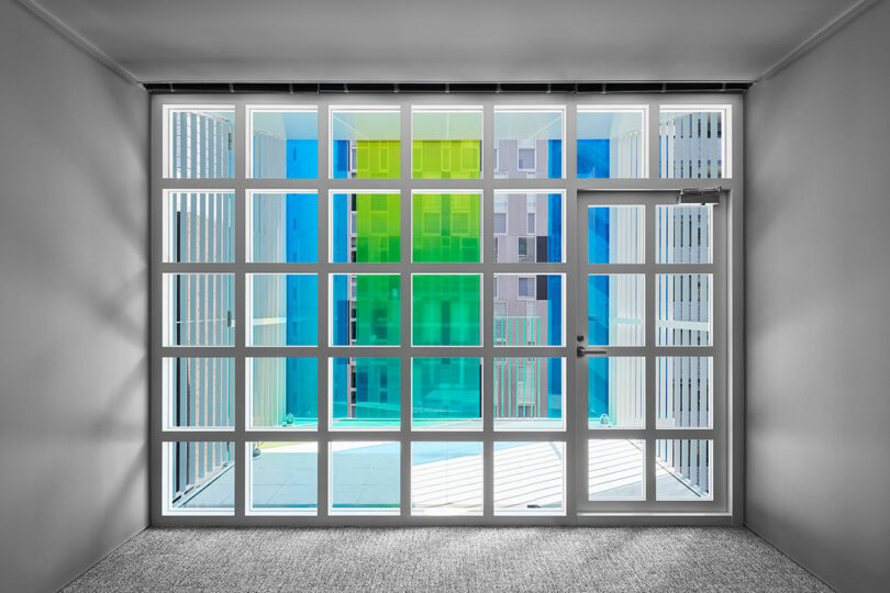 interior view of modern office space looking out to balcony with blue and green exterior glass