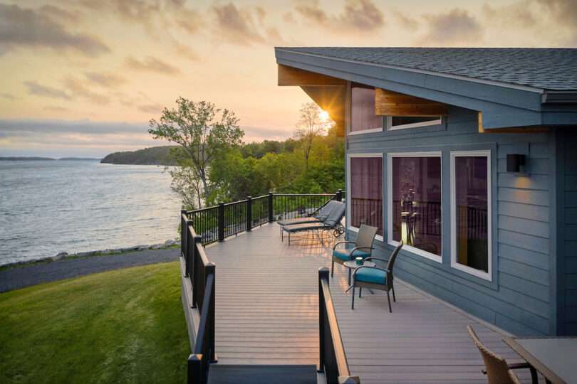 Lakeside home at sunset with patio seating and a scenic view.
