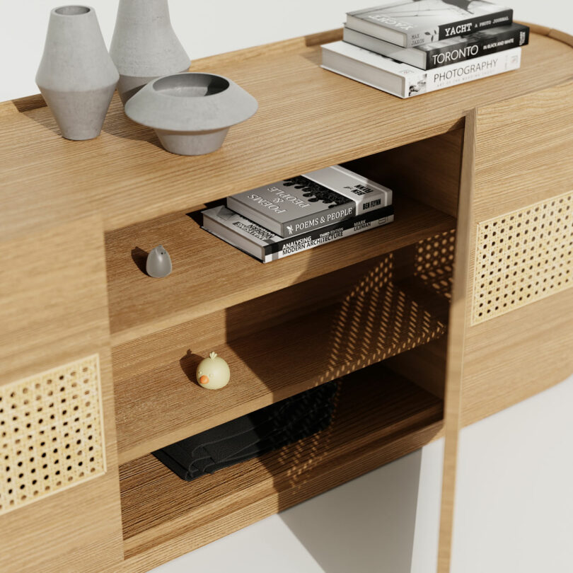 A wooden console sideboard with vases, books, and cat furniture on it.