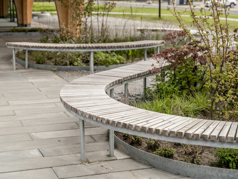 A curved wooden bench is located in front of a building.
