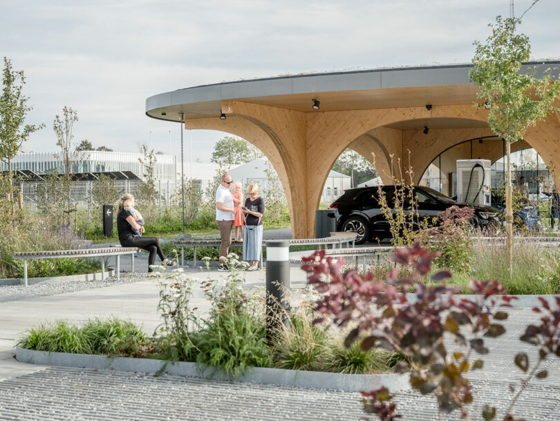A wooden structure with benches and plants in front of a charging park.