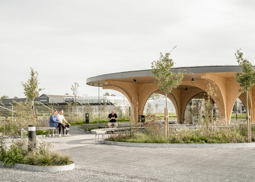 A wooden pavilion where people are sitting, resembling a charging park.