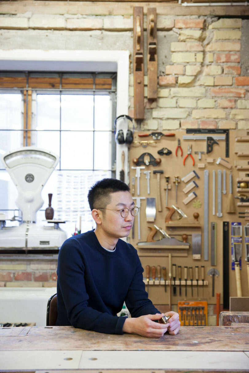 A gentleman sitting at a work table in a shop.