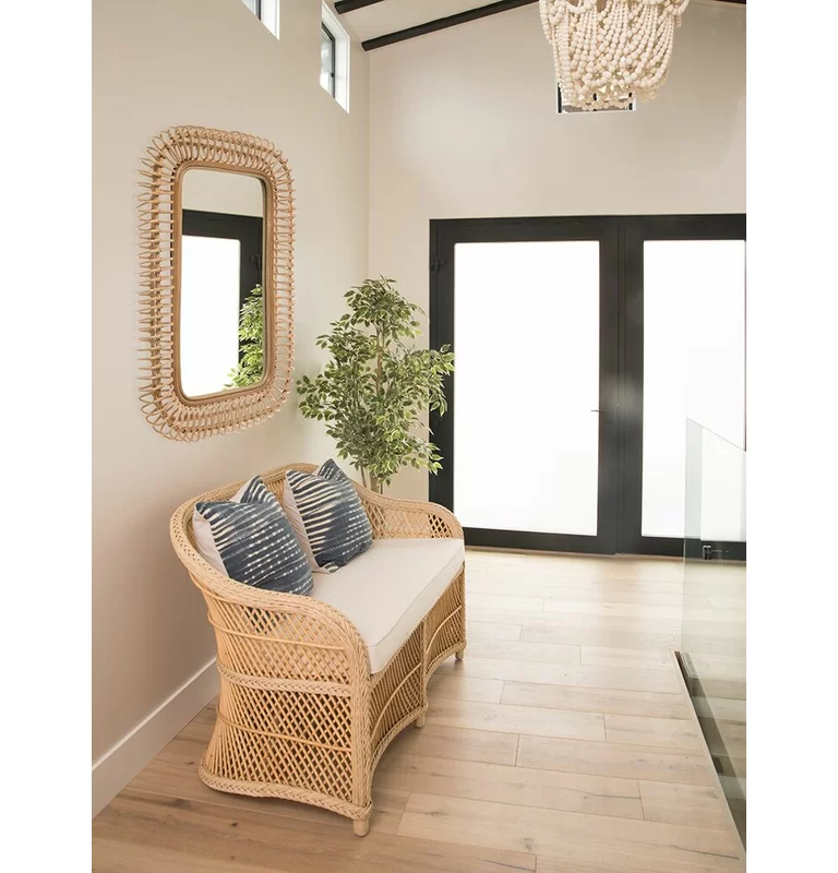Rattan Wall Mirror hanging on wall in entryway above a rattan loveseat