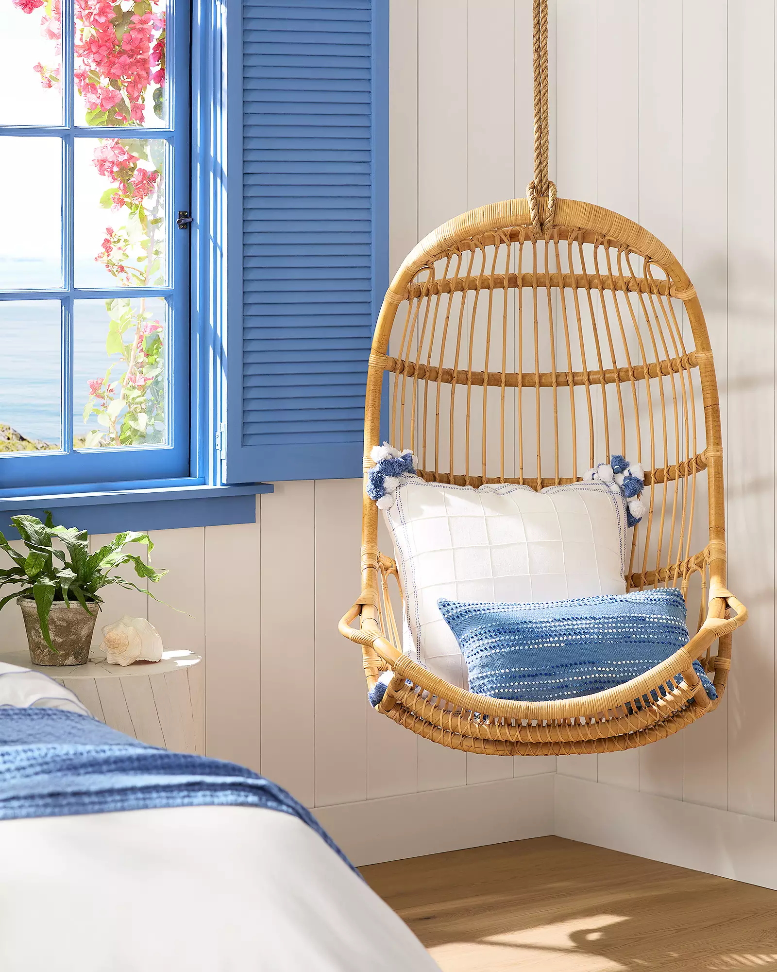 hanging rattan chair in room with blue theme boho coastal decor