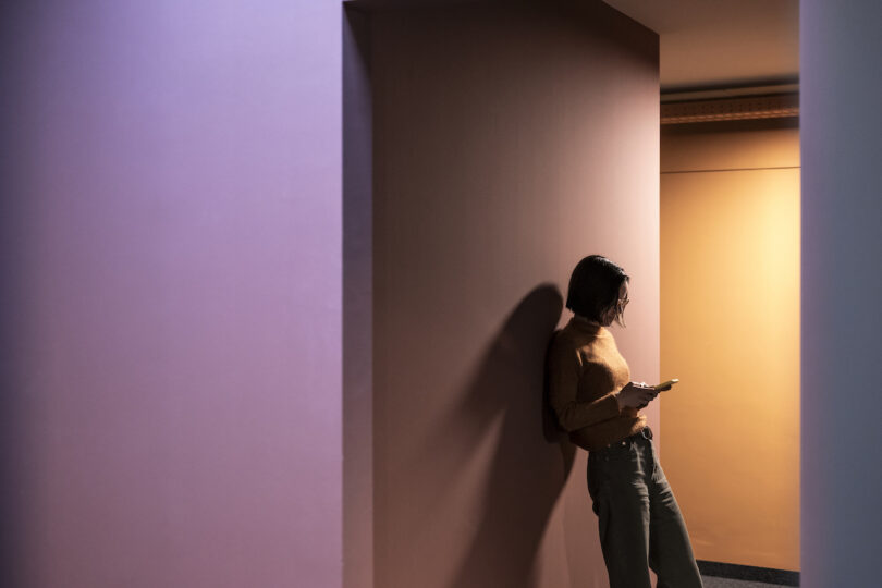Woman standing in a corridor looking at her phone, with her shadow cast on the NOA.