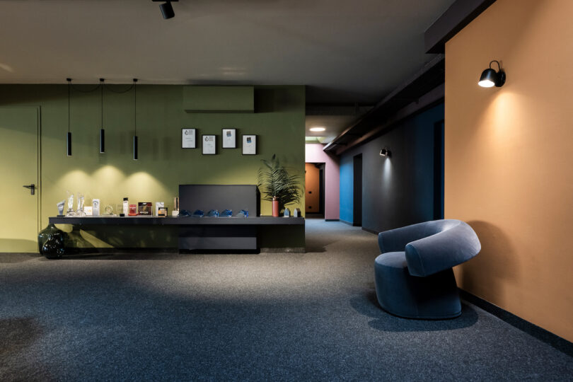 Modern office lobby with a reception desk, minimalist furniture, and colorful NOA walls.