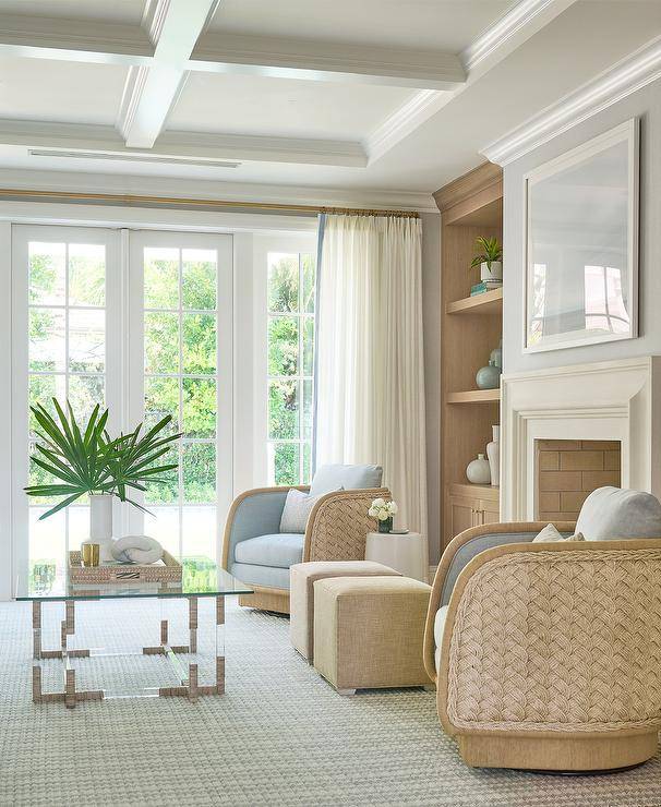 Morgan Harrison Home - Beige cube stools sit on a blue striped rug between blue and brown rope swivel chairs positioned in front of a limestone fireplace and facing a glass and rope coffee table under a coffered ceiling.