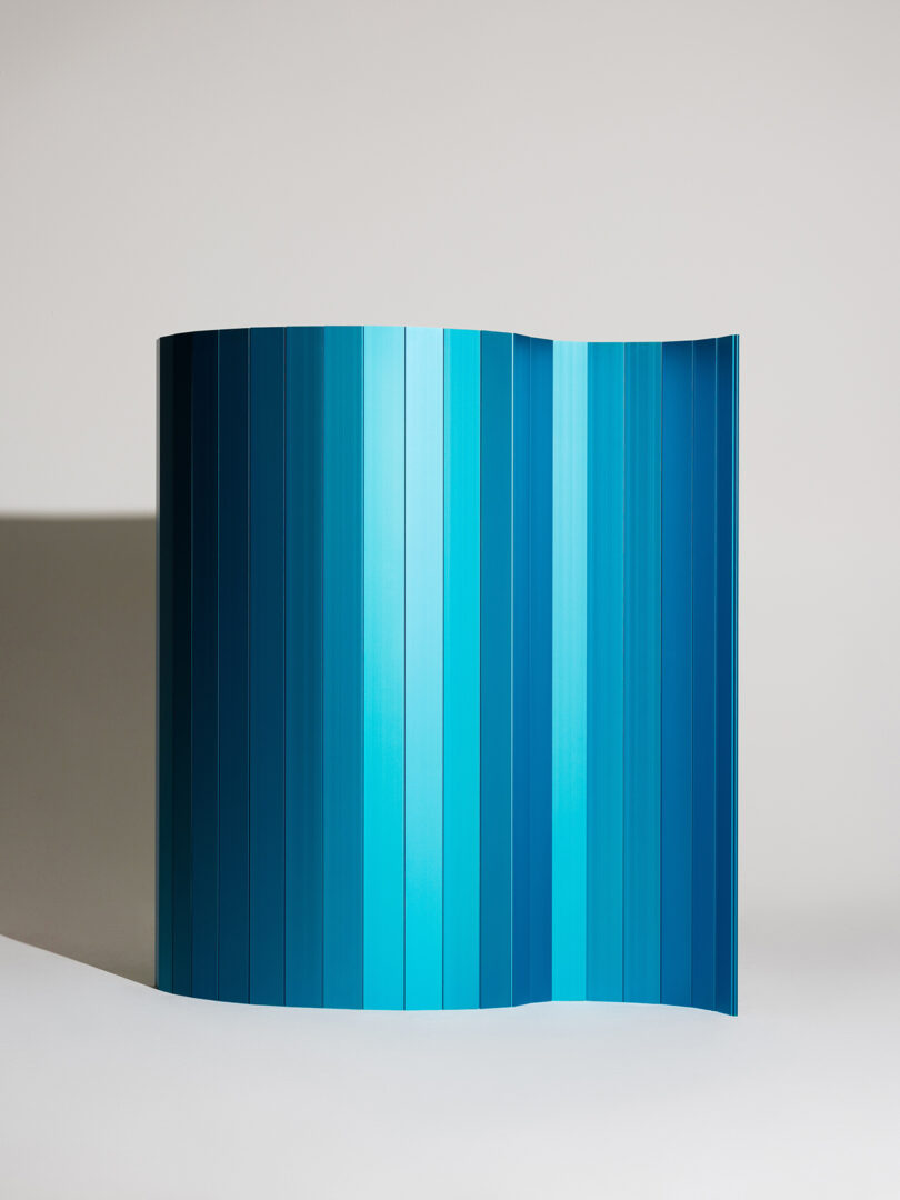A freestanding folded panel displaying a gradient of blue shades against a neutral background.