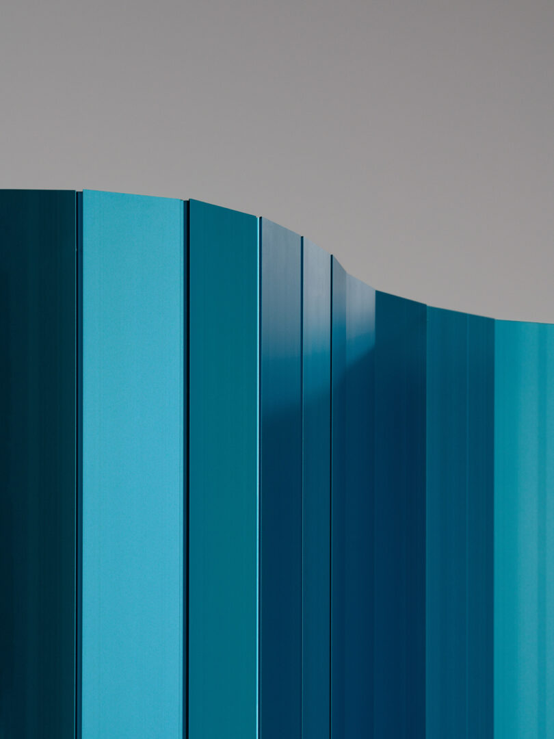 Detail of a freestanding folded panel displaying a gradient of blue shades against a neutral background.