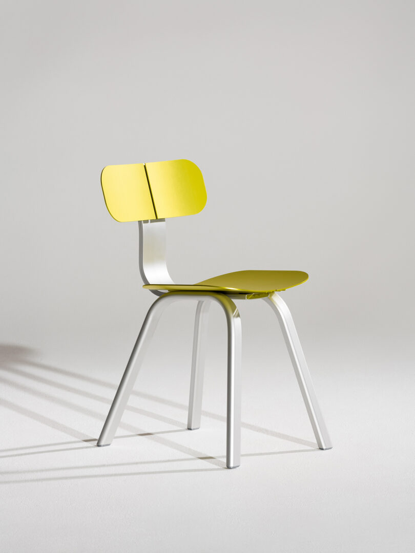 A modern chair with a vibrant yellow seat and backrest, positioned on a plain, light background.