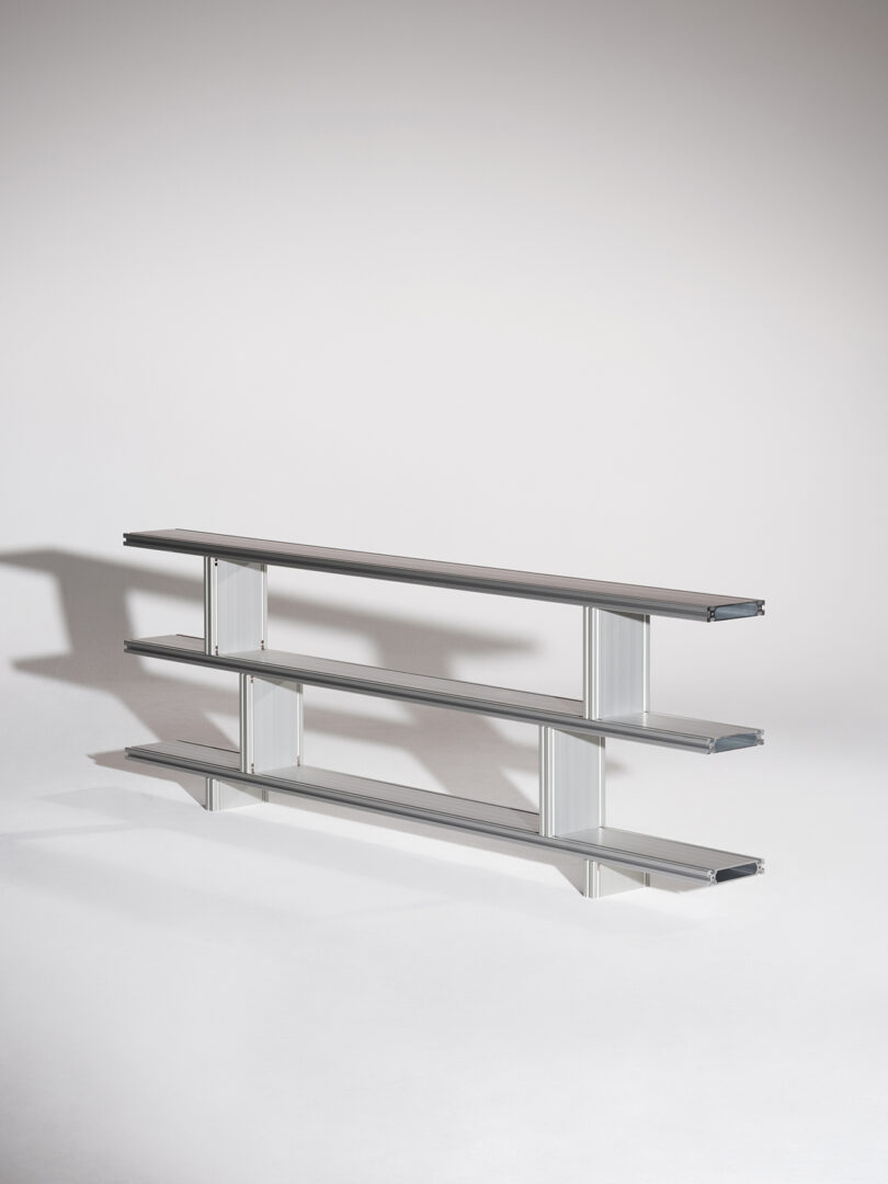 Modern three-tiered metal shelf unit on a neutral background.