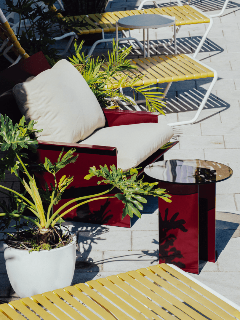 metal red chair next to metal red side table and potted plants outdoors