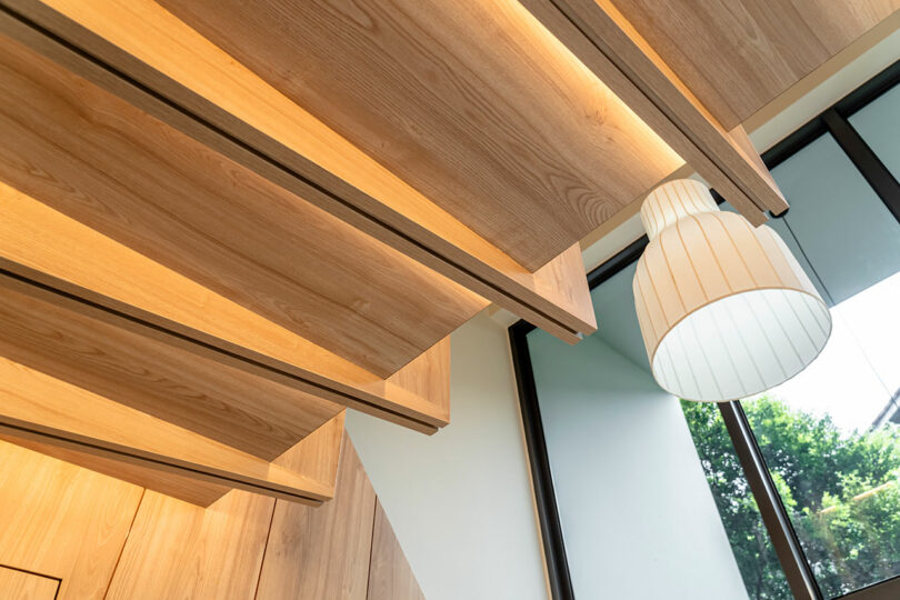 up view of a wood slatted ceiling with embedded lighting under loft