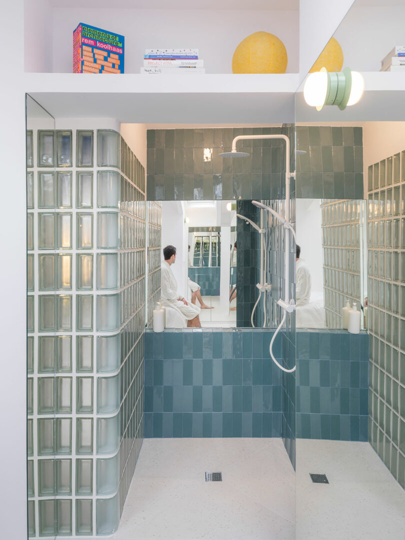 Modern bathroom with glass block walls and a person reflected in the mirror.