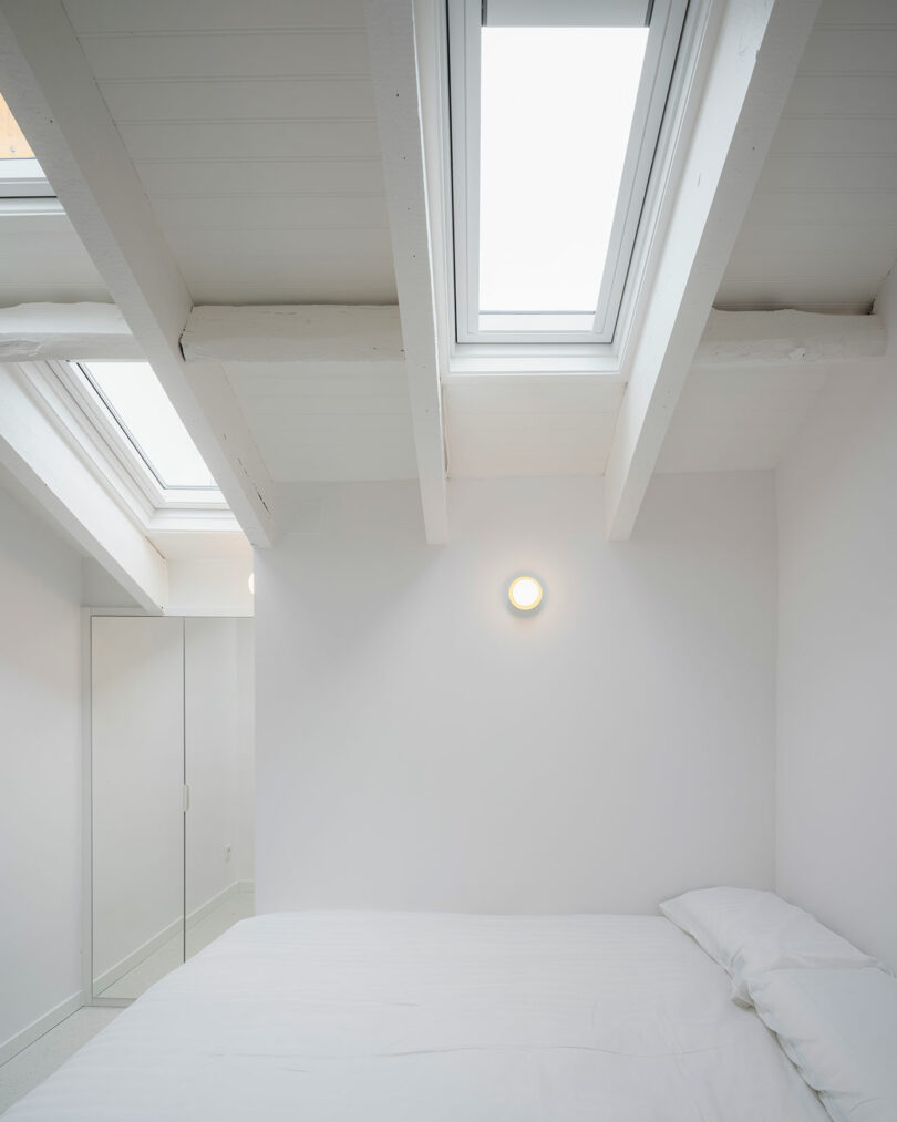 minimalist white bedroom with slanted ceiling with skylights