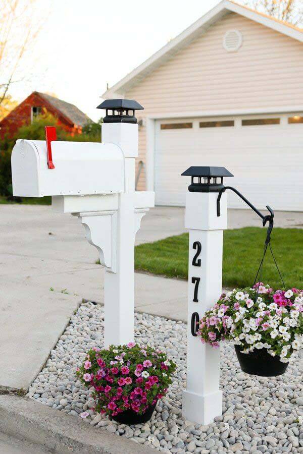 white pillar mailbox and white solar light with planters