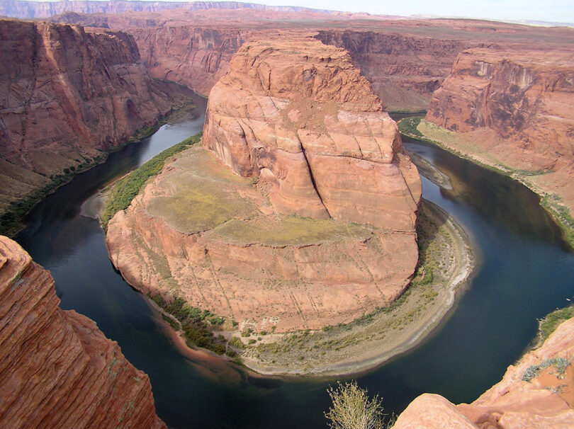 Aerial view of horseshoe bend, showing the colorado river winding around a rock formation in a desert landscape.