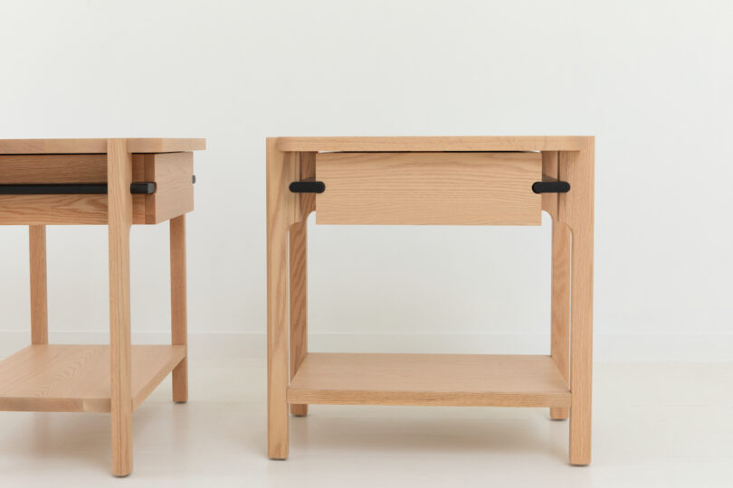 Two wooden nightstands with a single drawer, featuring black handles, against a white background.