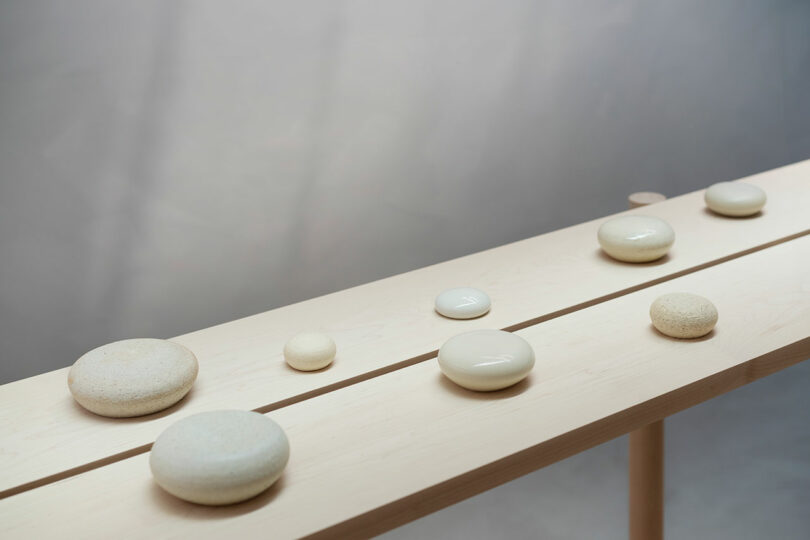 Smooth stones of various sizes arranged in a line on a wooden bench against a softly blurred background.