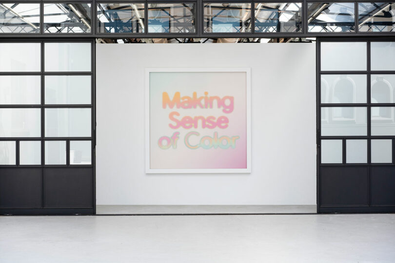 Large framed poster titled "Making Sense of Color" hanging on a white wall in a bright room with black framed windows.