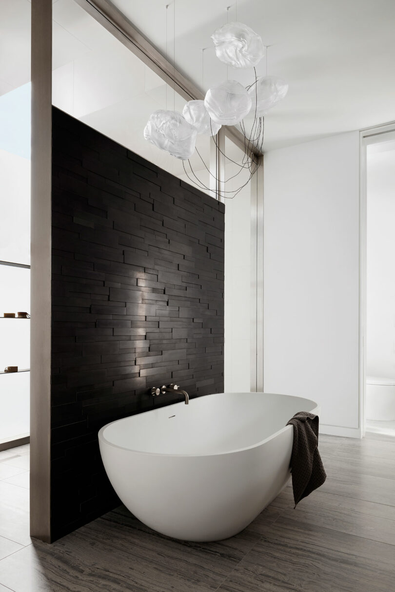 Modern bathroom with a freestanding bathtub and artistic glass lighting installation.