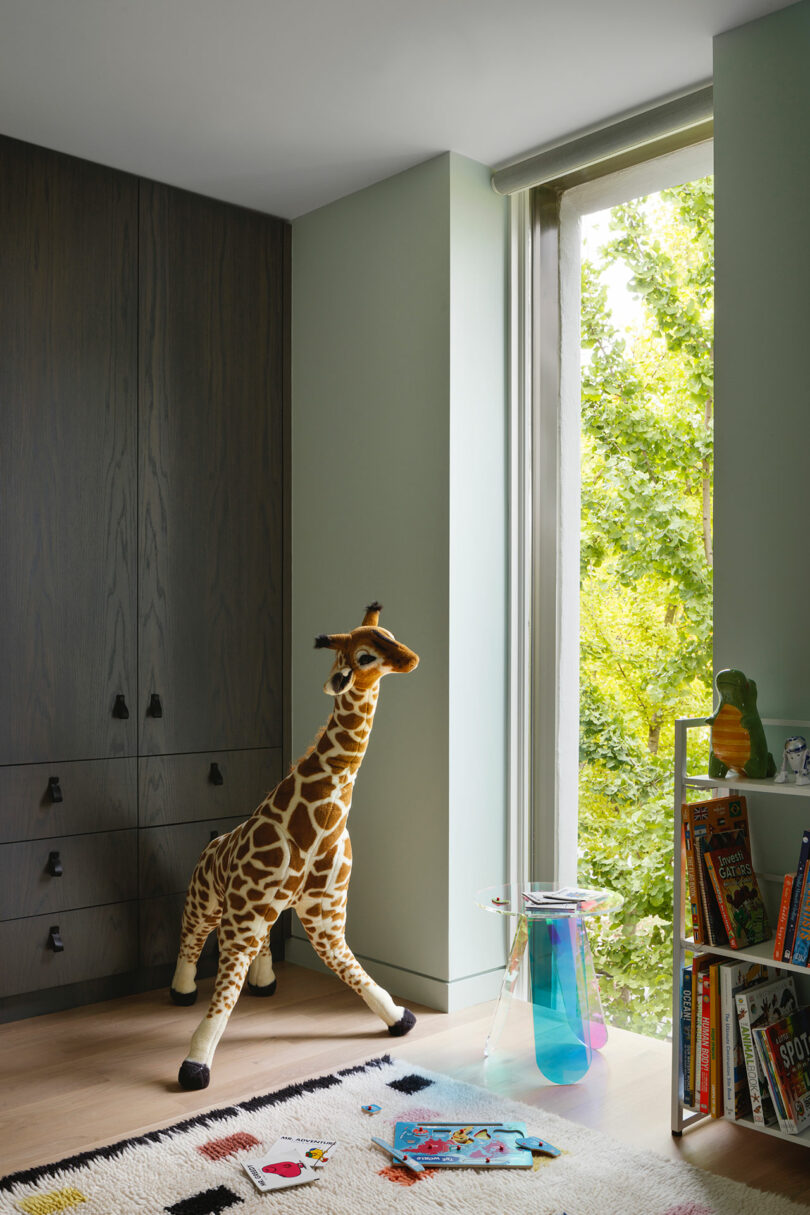 corner view of modern child's bedroom with large giraffe stuffed animal in front of window
