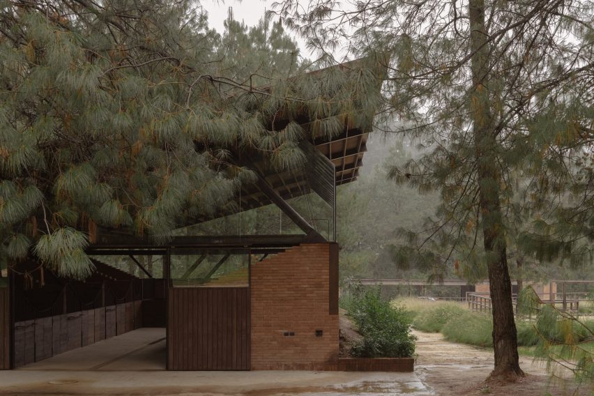 Side view of mono-pitched building seen through the trees