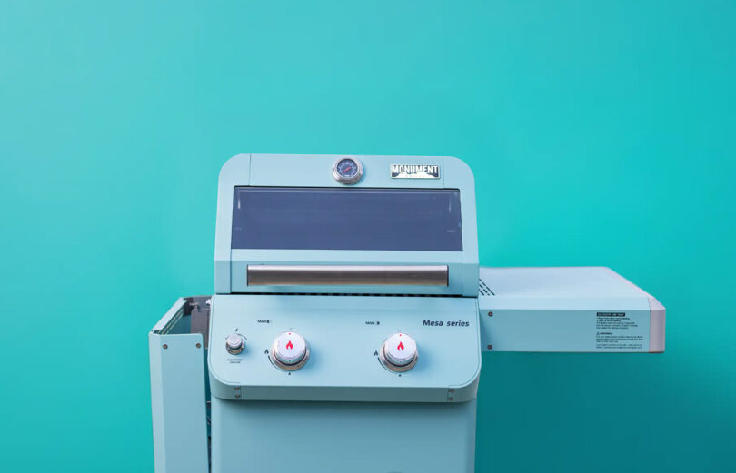 Teal Monument Grills Mesa Collection propane gas grill with right side table extended out staged against a teal background.