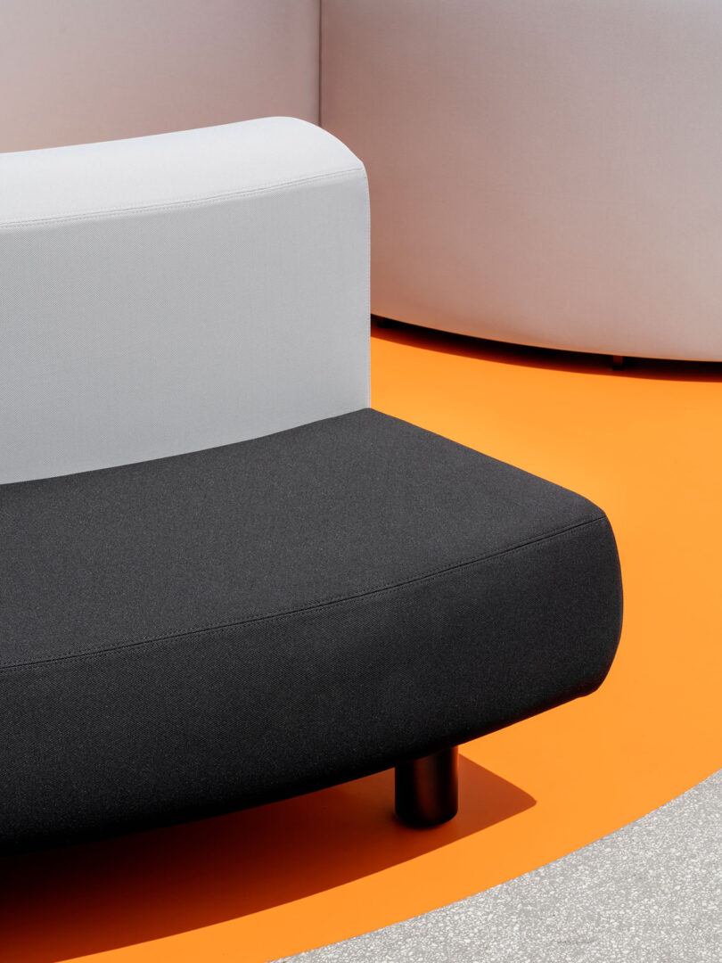 Modern furniture with a two-tone couch on an orange carpet.