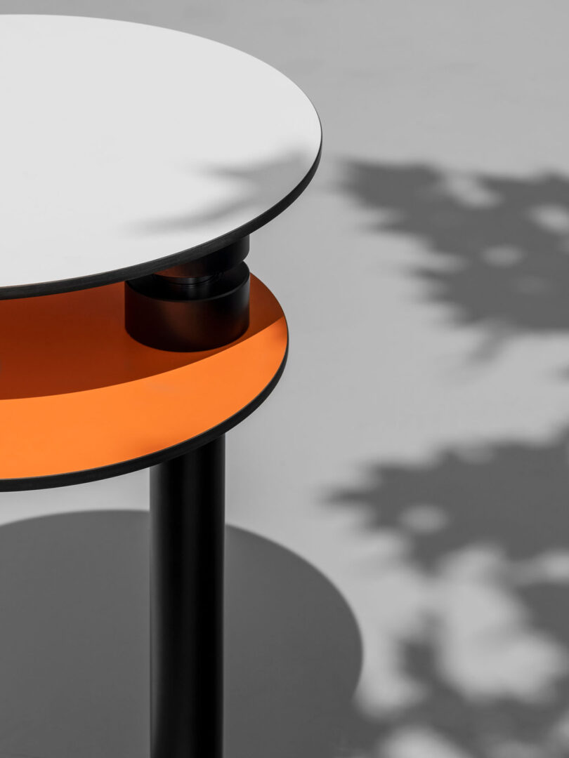 Modern round two-tiered side table with a black and orange color scheme..