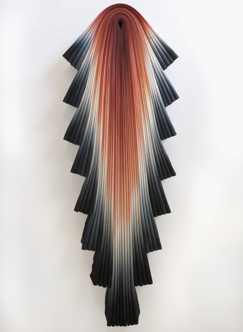A wall-mounted art sculpture resembling a cascading wave of colored fabric.