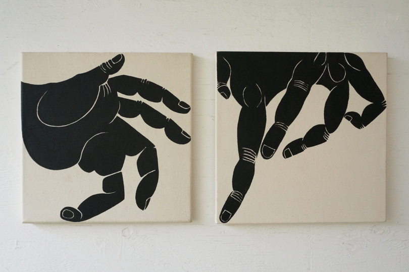 Two canvas paintings featuring stylized black and white images of hands.