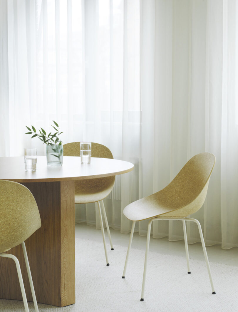 shell chairs around a round table next to windows