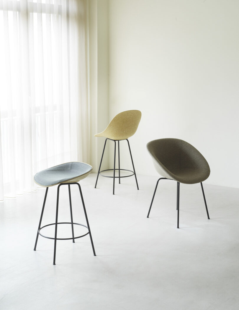 three shell chairs next to a window with curtains