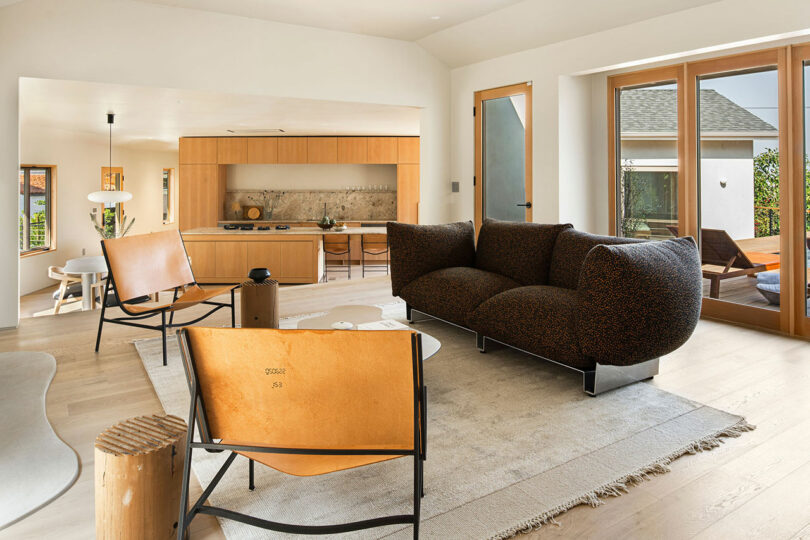 angled interior view of a modern minimalist home with a seating area looking into light wood kitchen.