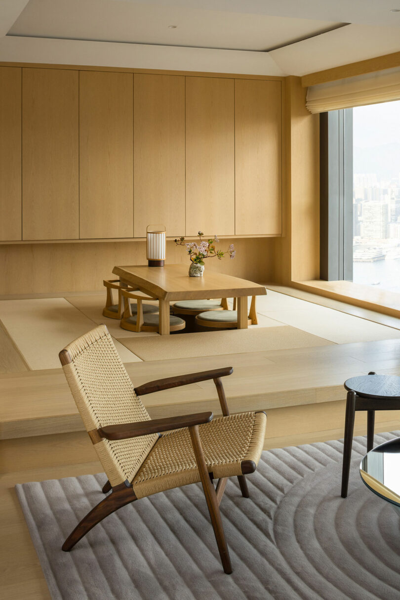 Minimalist dining room featuring wooden paneling, a table with chairs, and a city view from the adjacent window.