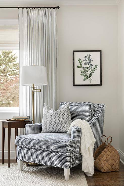 Cottagecore style bedroom features a black and white houndstooth corner chair lit by a brass floor lamp.