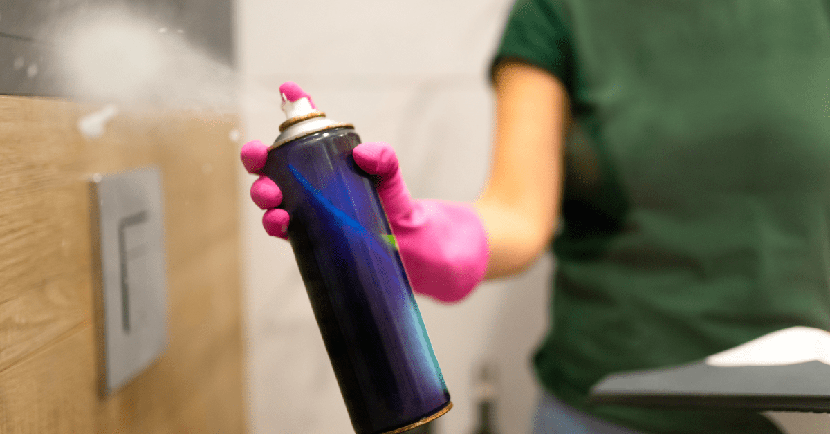 A person using a spray-on glass shower cleaner onto glass shower.