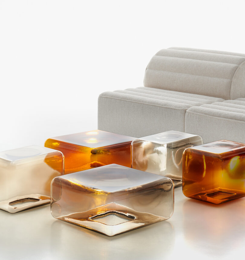five translucent and amber glass tables arranged neatly on a white surface next to a white sofa
