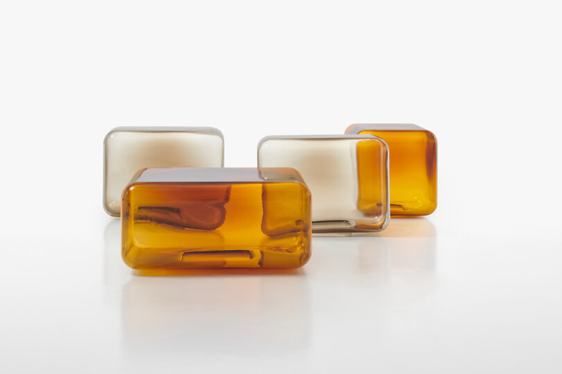 four translucent and amber glass tables arranged neatly on a white surface